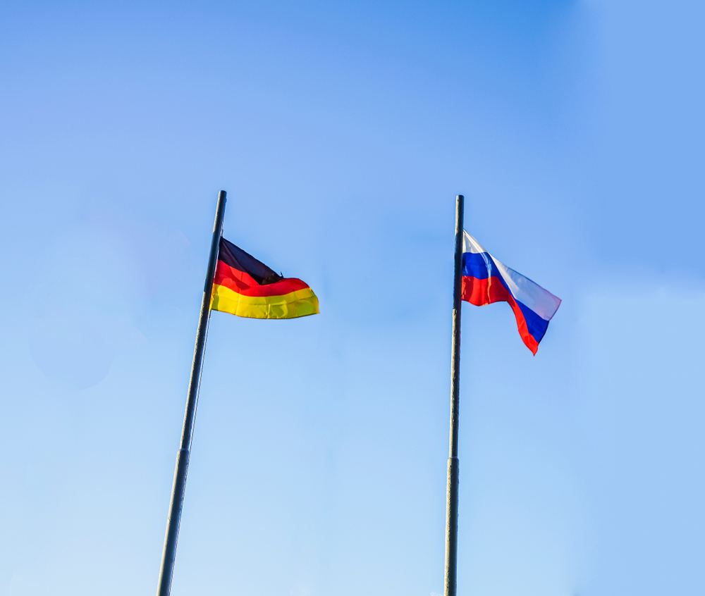 Russia,And,Germany,Flag,Waving,In,The,Wind,Against,Blue